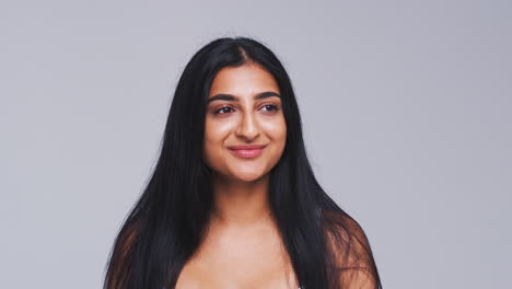 Head-And-Shoulders-Studio-Shot-Of-Calm-Woman-Smiling-At-Camera-In-Slow-Motion