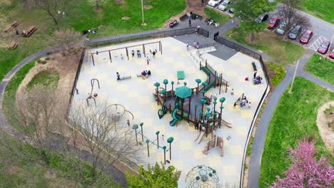 children and families play on playground equipment at community public park