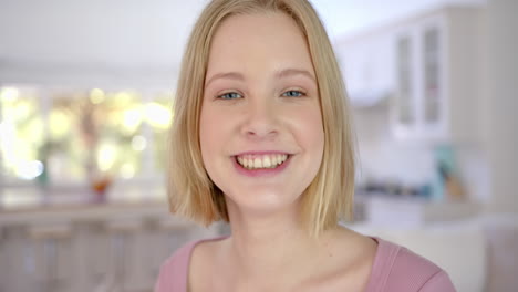 Portrait-of-happy-caucasian-female-teenager-with-blond-hair-at-home,-slow-motion