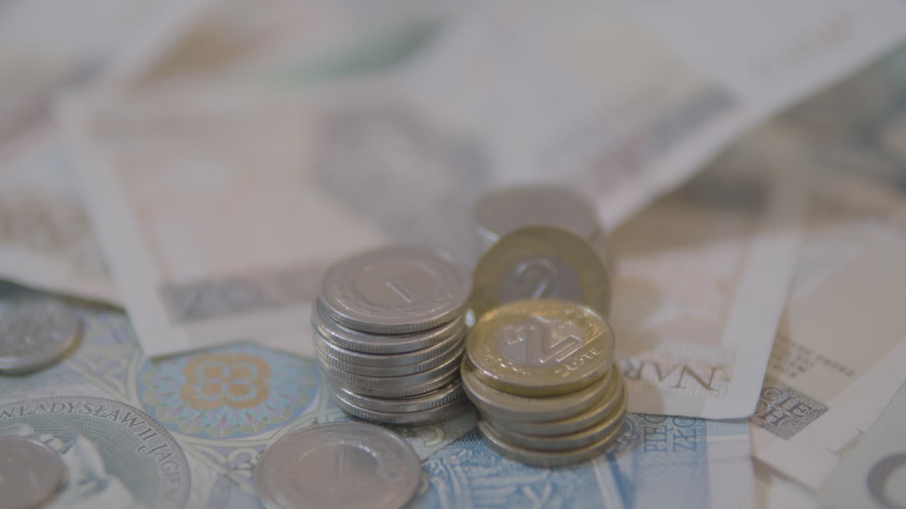 tiro inclinado hacia arriba de muchos billetes de zloty polacos y monedas apiladas en la mesa, primer plano