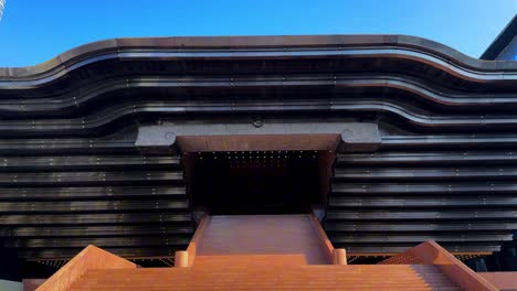 amplias escaleras conducen a una estructura futurista y geométrica bajo un cielo brillante