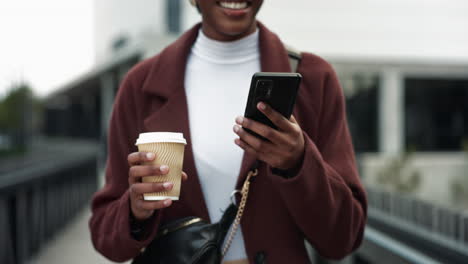 woman walking in the city with a coffee and using her phone