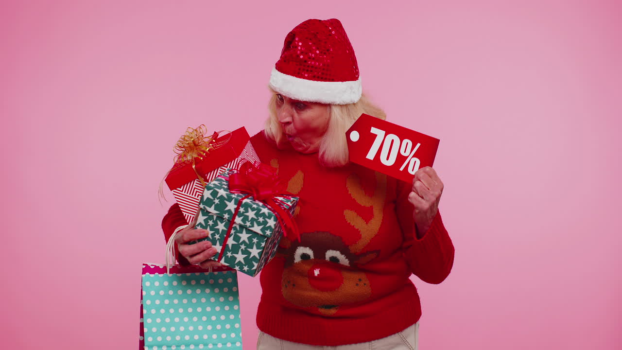 mujer madura en suéter de navidad mostrando caja de regalos y 70 por ciento de descuento inscripciones texto de pancarta