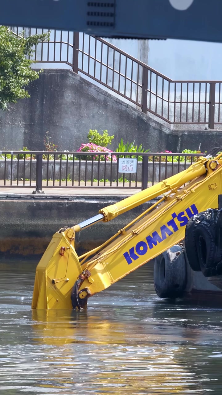Escavatore industriale su una chiatta che draga un canale fluviale cittadino a Tokyo, Giappone