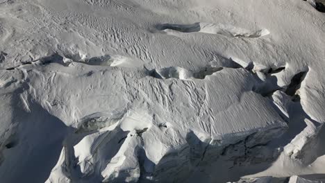 vista aérea, terreno montañoso cubierto de nieve, las grietas están ocultas con el polvo