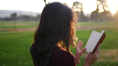 Eine-Junge-Frau-Liest-Draußen-Im-Park-Bei-Sonnenuntergang-Ein-Märchenbuch,-Während-Das-Licht-Hell-Scheint