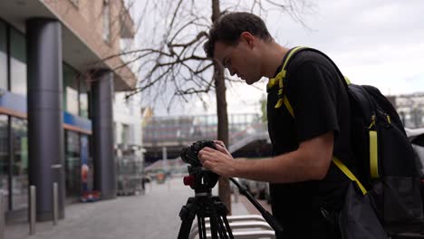 young caucasian man is holding his camera and adjusting his camera settings on the screen