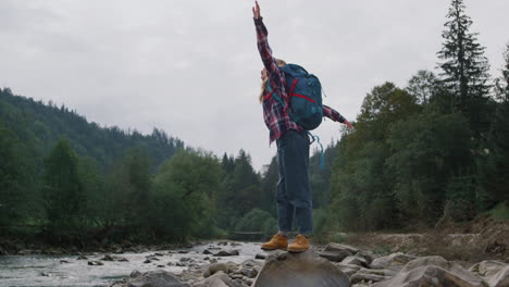 woman raising hands in mountain landscape