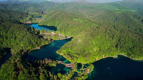 cinematic aerial view of plitvice lakes surrounded by lush green forests in croatia