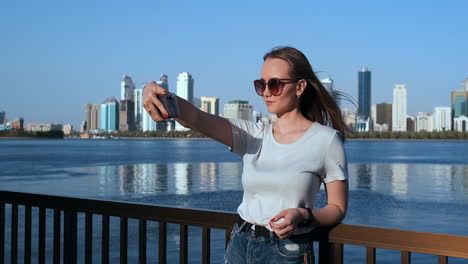 caucasian-woman-is-taking-selfies-by-mobile-phone-outdoors-in-Dubai-Marina-in-sunny-day.