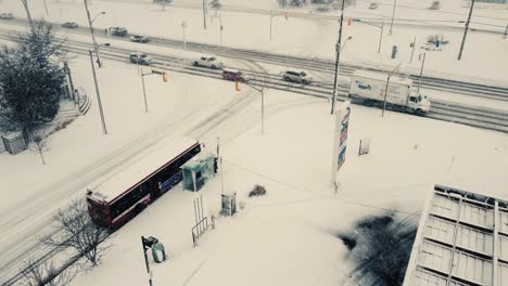 Public-bus-parked-at-snowy-stop-shelter-on-busy-Toronto-intersection,-Ontario-Canada