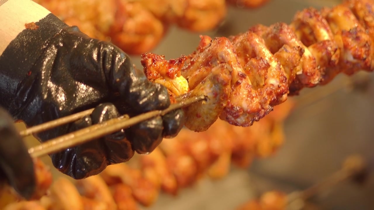 Chef che prepara ali di pollo condite su spiedini per la griglia