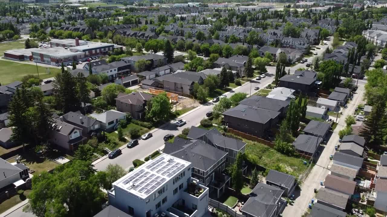 drone volando sobre casas nuevas cerca de una escuela en un día soleado en calgary