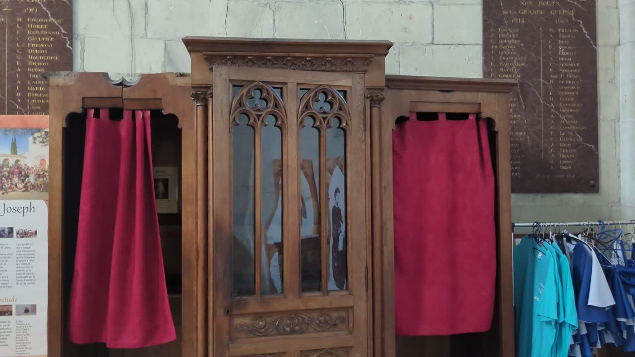 사제와 고백자가 죄를 드러내고 용서를 구하기 위해 교회에서 사생활 커튼을 가진 종교 고백 부스 4k