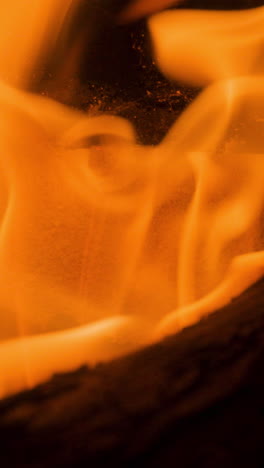 a close up of flames in log fire burning in a fireplace in vertical