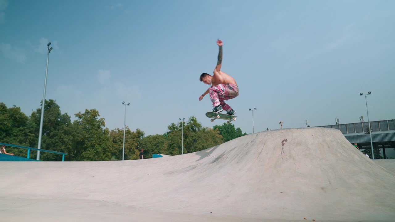 Ung mannlig skateboarder utfører et ollie-triks i en skatepark.