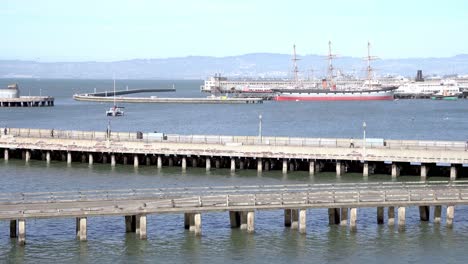 people walking by the piers and ships stationary in the bay