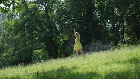 woman in yellow dress dancing by tree in summer park