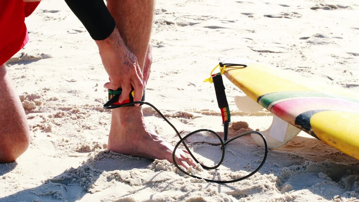 Uomo anziano che lega il leash della tavola da surf alla caviglia