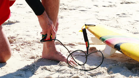 hombre mayor atando la correa de la tabla de surf al tobillo