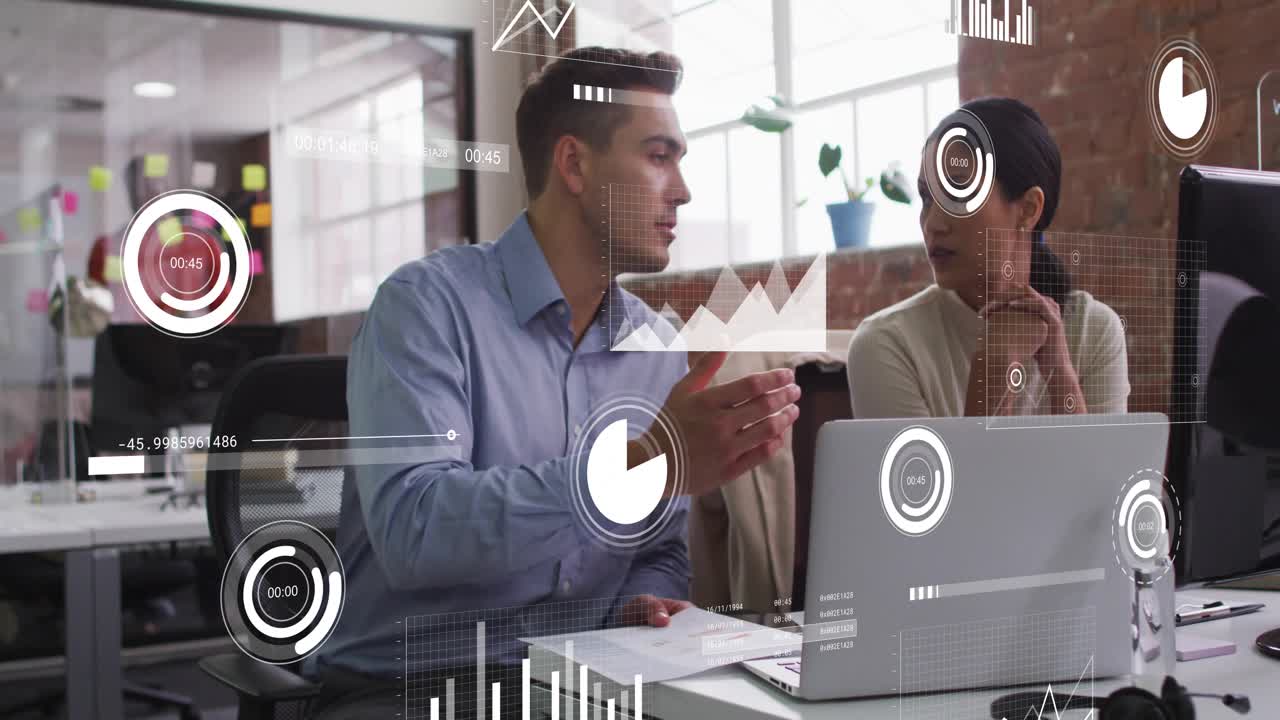 Male analyst turning from docs, explaining to woman, animated graphs highlighting laptop analytics