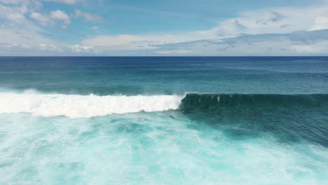 slow motion aerial tracking left as wave breaks crashing and mist spray rises off top, south pacific, rarotonga cook islands