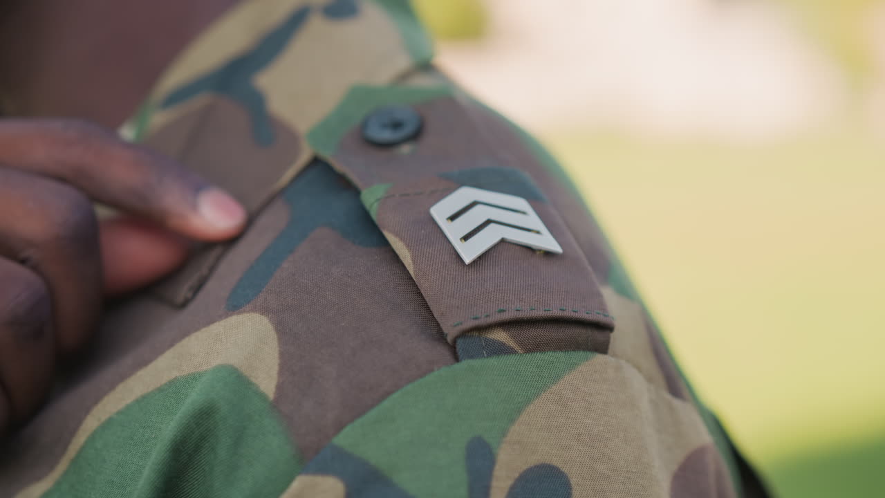 Sergeant Adjusts Insignia Before Ceremony, Soldier Carefully Affixes Badge Prior To Event, Service Member Gently Positions Badge On Shoulder Before Formal Promotion Ceremony In Sunlight
