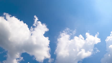 bright summer sun illuminating the soft white clouds. rays of sun go through the clouds. low angle view. timelapse.