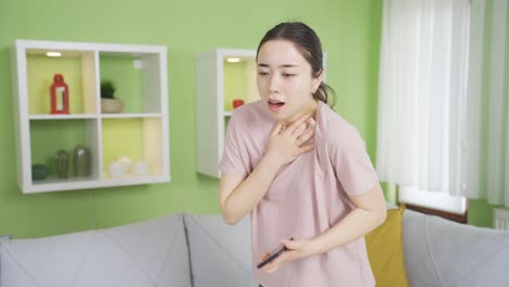 Asian-young-woman-experiencing-prolonged-shortness-of-breath-at-home,-chest-tightness.