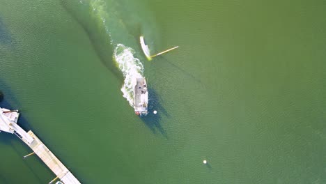 aerial top down of wrecking tug, towing and dragging submerged sailboat towards the dock