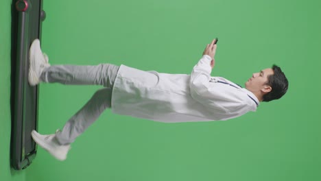 병원에서 녹색 화면 배경에서 는 동안 스마트폰을 사용하여 스테토스코프를 가진 아시아 남성 의사