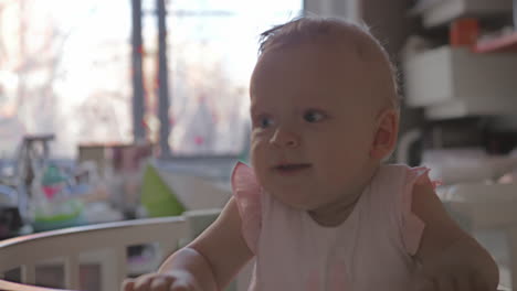 a smiling baby girl standing in a crib