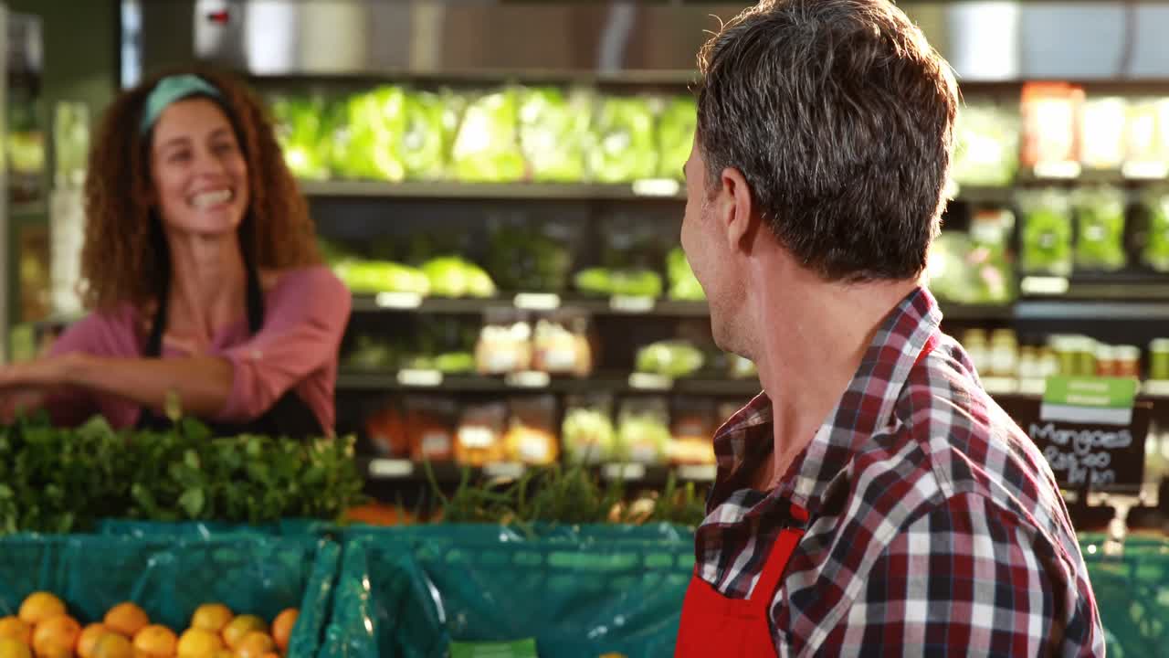 Personal sonriente entre sí en la sección de productos orgánicos