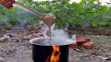 a man cooks chai tea over an open flame on a farm in india