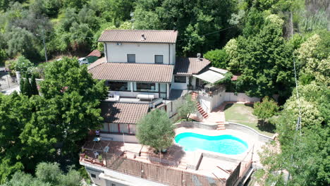 slow aerial dolly of small mediterranean villa with pool surrounded by trees