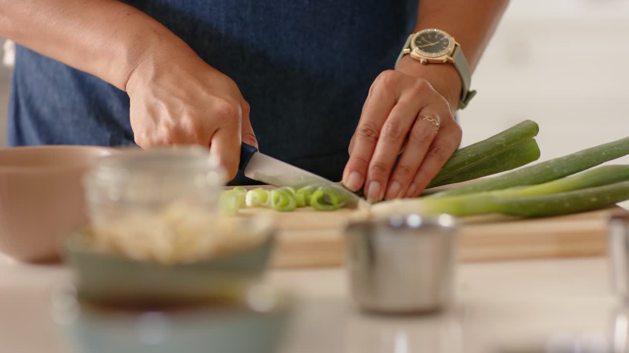 Anziana donna africana che sistema un cipollotto e un coltello da chef, tagliando con movimento oscillatorio su un tagliere in cucina per un pasto.