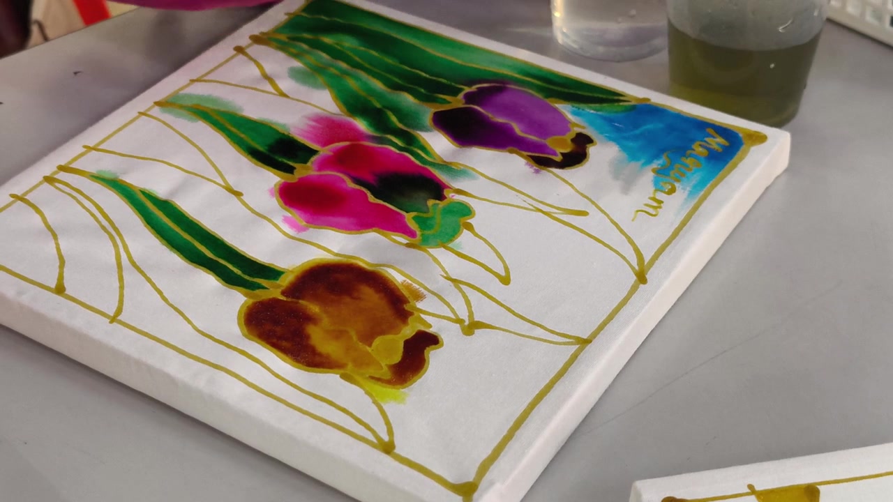 Primo piano di un bambino che dipinge con tinture colorate su una tela batik tradizionale malese. Giovane studente che apprende l'artigianato del patrimonio culturale attraverso l'arte pratica. Attività educativa che introduce l'autentica arte popolare.