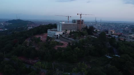 drone moves toward mokola hill showing premier hotel under reconstruction, cranes, and ibadan city in the background.