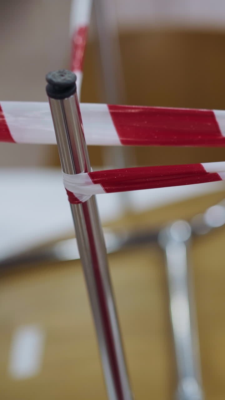 Metal legs of chairs wrapped with colorful warning red and white strip standing upside down on table in closed restaurant in shopping mall closeup