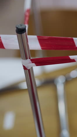 Metal legs of chairs wrapped with colorful warning red and white strip standing upside down on table in closed restaurant in shopping mall closeup