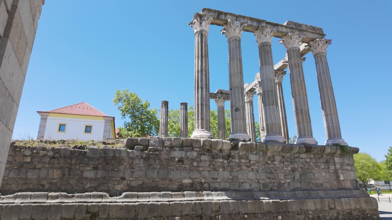 Majestic ruins of the Roman Temple of Evora in Portugal, with Corinthian columns reaching for the clear blue sky. Pan Right