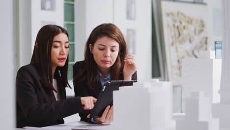 especialistas tomando notas en la tableta después de revisar el modelo de construcción