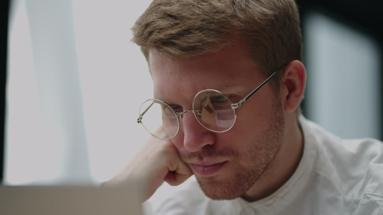 hombre caucásico inteligente con gafas está leyendo información en la pantalla de la computadora portátil, vista de cerca de la cara