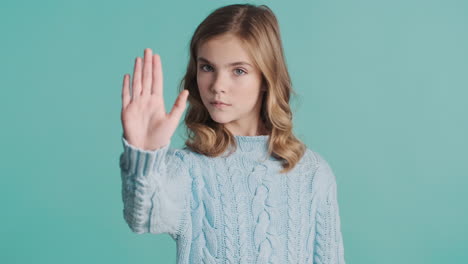 teenage caucasian girl doing stop gesture in front of the camera.