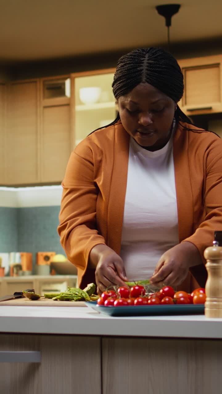 Video verticale: Vlogger culinaria afroamericana che spalma fette di avocado su toast di pane per una scelta salutare.