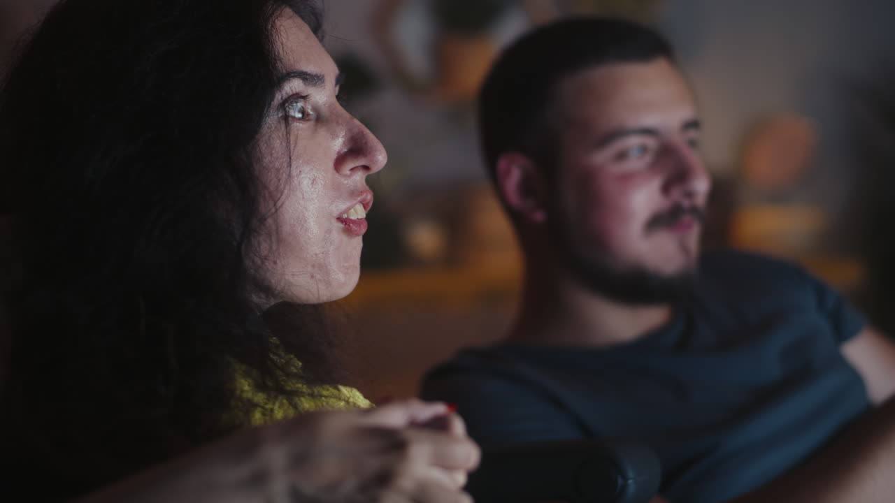 Scared young married couple embracing while watching horror movies at cozy home