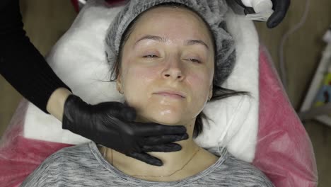 Cosmetologist-applies-peeling-lotion-on-woman-face-in-beauty-clinic-salon