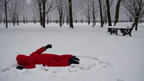 child playing in a snowy park, making snow angels