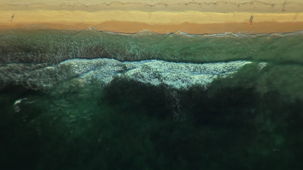 vista aérea de las olas que se estrellan en una playa de arena