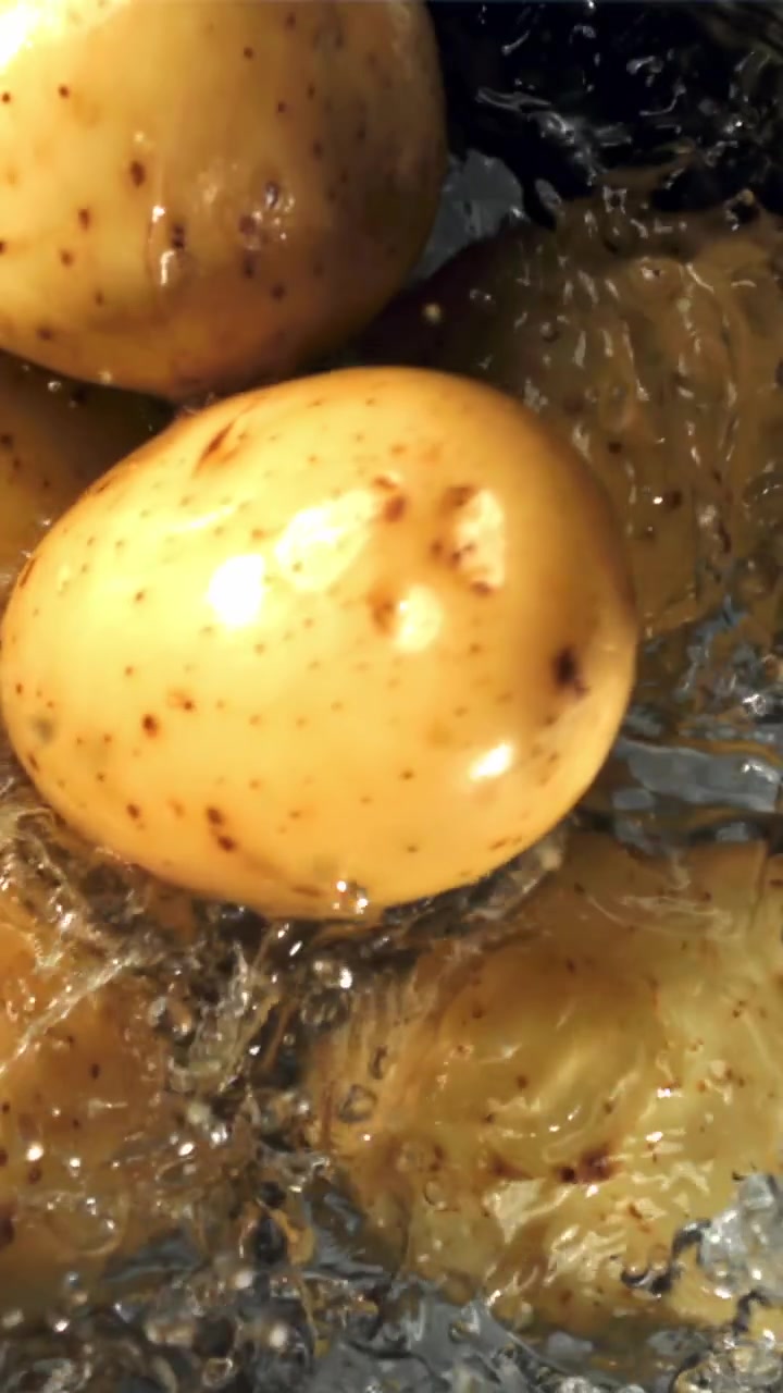 Patate fresche che si tuffano nell'acqua in una pentola al rallentatore